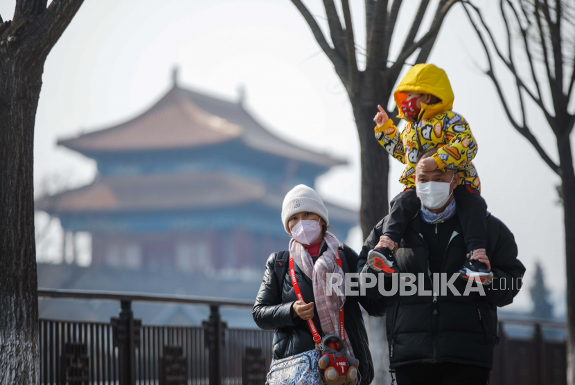 Tourists wearing face masks walk near the Turret of the Palace Museum in Beijing, China, 22 February 2023. Cina menjadi semakin berambisi dengan target pertumbuhan 2023.