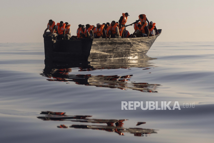 Para migran dengan jaket pelampung yang disediakan oleh sukarelawan Ocean Viking, kapal pencari dan penyelamat migran yang dijalankan oleh LSM SOS Mediterranee dan Federasi Palang Merah Internasional (IFCR), masih berlayar dengan perahu kayu saat mereka diselamatkan  Sabtu, 27 Agustus , 2022, sekitar 26 mil laut selatan pulau Lampedusa Italia di laut Mediterania. 87 orang yang selamat, termasuk 3 wanita, 25 anak di bawah umur diselamatkan dalam operasi penyelamatan.