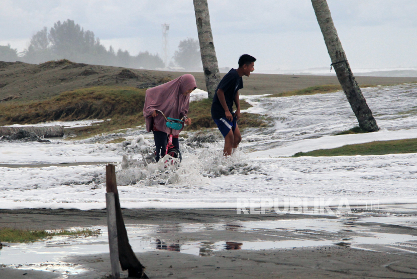Sejumlah anak melintasi genangan banjir rob di Desa Gampong Belakang, Johan Pahlawan, Aceh Barat, Aceh, Sabtu (11/7/2020). Banjir rob tersebut mengakibatkan ratusan rumah warga terendam.