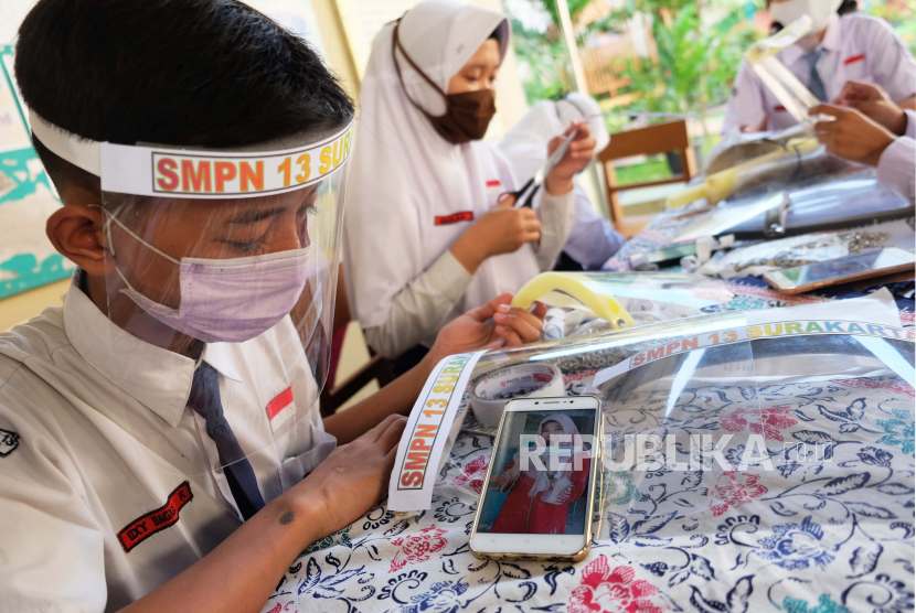 Siswa membuat pelindung wajah (face shield) dengan dibantu guru di halaman SMP Negeri 13 Solo, Jawa Tengah, Jumat (12/6/2020). Sekolah setempat memberikan bahan untuk membuat pelindung wajah bagi para siswa sebagai persiapan pelaksanaan Kegiatan Belajar Mengajar (KBM) menjelang tahun ajaran baru 2020/2021 yang disesuaikan dengan protokol penanganan pandemi COVID-19, jika Solo menerapkan situasi normal