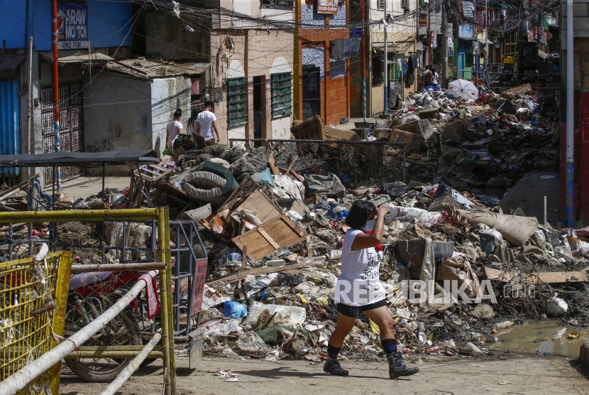  Seseorang berjalan melewati sampah dan puing-puing di jalan di komunitas tepi sungai yang terkena dampak banjir di Kota Marikina, Metro Manila, Filipina 18 November 2020. Sekelompok pendaur ulang di Filipina berusaha meredakan krisis sampah plastik di negara itu. 