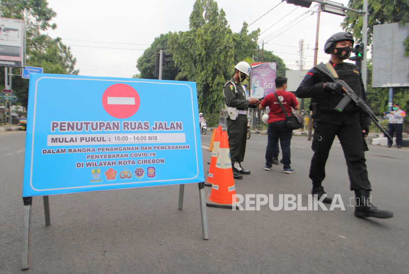 Petugas Dinas Perhubungan dan personel Brimob berjaga di ruas jalan Siliwangi, Kota Cirebon, Jawa Barat saat Pembatasan Aktivitas Masyarakat. Ilustrasi