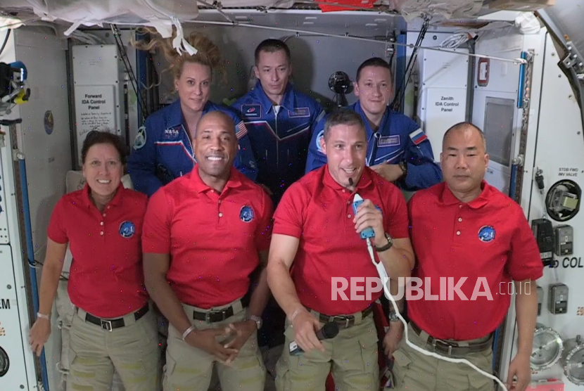 Foto diam yang diambil dengan video handout yang disediakan oleh NASA menunjukkan anggota kru (merah) pesawat luar angkasa milik SpaceX Crew Dragon milik pribadi yang membawa empat astronot kru komersial berpose untuk kamera setelah disambut di Stasiun Luar Angkasa Internasional (ISS) setelah berhasil merapat, 16 November 2020 (dikeluarkan 17 November 2020) dalam misi penting dalam perjalanan luar angkasa. 