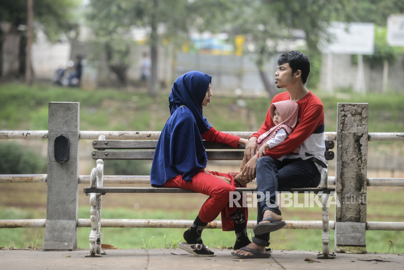 Sejumlah warga duduk di bangku taman saat ngabuburit di kawasan Banjir Kanal Timur, Jakarta. Disdik DKI Jakarta meminta orang tua memantau anak agar tidak berkumpul ngabuburit.
