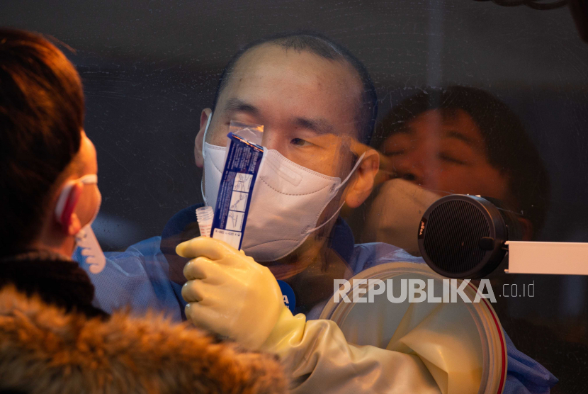 Seorang petugas kesehatan (kanan) mengumpulkan swab dari seorang warga untuk pengujian penyakit coronavirus (COVID-19) di klinik darurat di luar balai kota Seoul di Seoul, Korea Selatan, 05 Januari 2021.