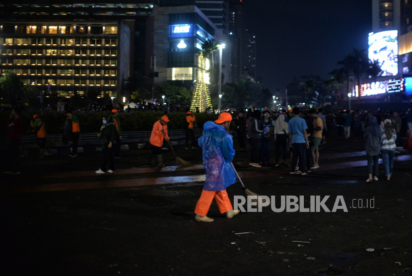 Petugas PPSU membersihkan sampah usai perayaan Tahun Baru 2023 di kawasan Bundaran Hotel Indonesia, Jakarta, Ahad (1/1/2023) dini hari. DLH DKI Jakarta sebut jumlah sampah tahun ini menurun 40 persen dibanding tahun lalu.