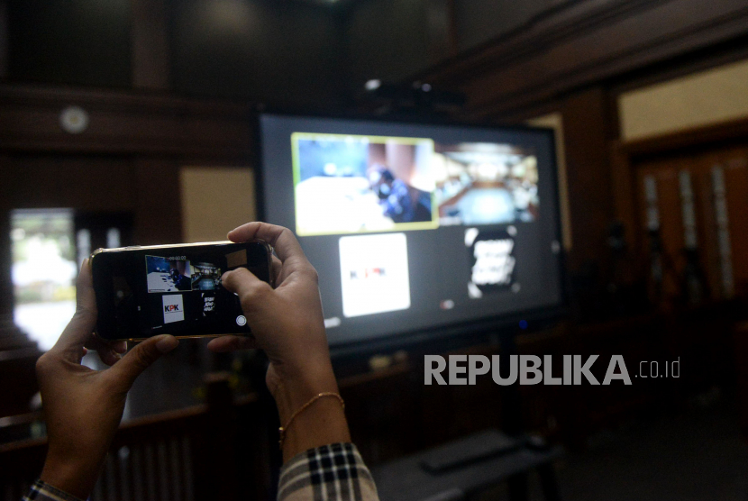 Jurnalis mengambil gambar layar yang menampilkan Mantan Sekretaris Mahkamah Agung (MA) Nurhadi bersama Menantunya Rezky Herbiyono sebelum mengikuti sidang pembacaan putusan secara virtual di Pengadilan Tipikor, Jakarta, Rabu (10/3). Majelis hakim menjatuhkan pidana penjara 6 tahun dan denda Rp500 juta subsider 3 bulan kurungan kepada terdakwa mantan Sekretaris Mahkamah Agung (MA) Nurhadi. Selain Nurhadi, Rizky Herbiyono yang juga terdakwa suap pengurusan perkara di MA dan gratifikasi divonis dengan 6 tahun penjara dan denda Rp500 juta subsider 3 bulan kurungan.Prayogi/Republika.