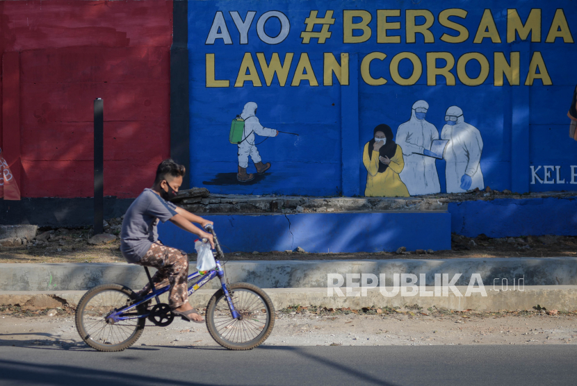 Warga berjalan melintasi mural bertema Covid-19 di kawasan Bukit Duri, Tebet, Jakarta Selatan. Epidemiolog dari Universitas Indonesia Pandu Riono memandang Pembatasan Sosial Berskala Komunitas (PSBK) cenderung lebih efektif ketimbang Pembatasan Sosial Berskala Besar (PSBB). 