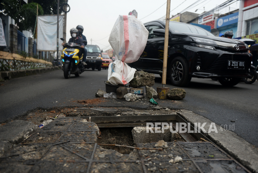 Pengendara melintas dekat jalan yang berlubang di Kawasan jalan Raya Pondok Gede, Bekasi, Jawa Barat, Senin (23/11). Kondisi jalan berlubang tersebut sangat membahayakan pengguna jalan serta mengakibatkan kemacetan.Prayogi/Republika