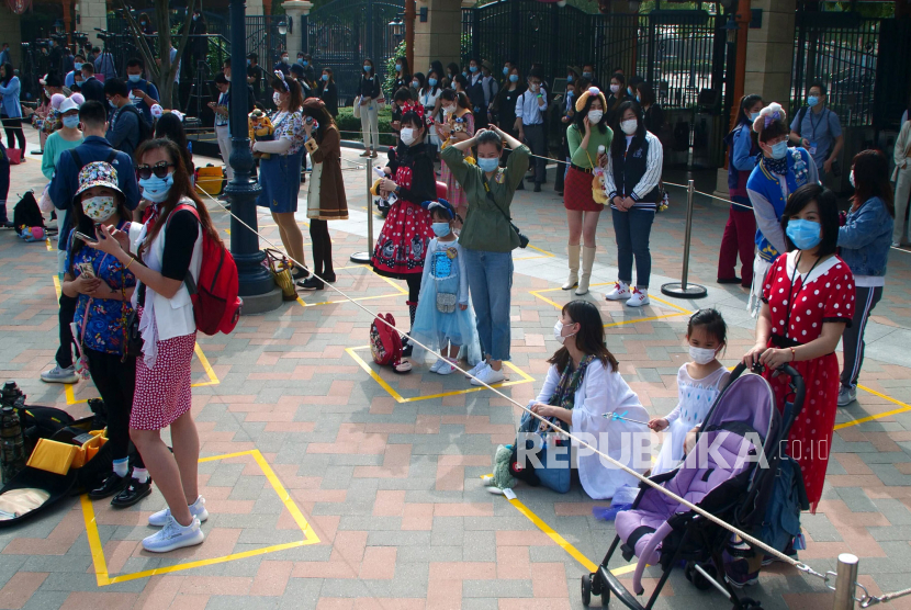 Pengunjung mengenakan masker menunggu untuk memasuki taman hiburan Disneyland saat dibuka kembali di Shanghai, China, Senin (11/4). Jumlah pengunjung akan dibatasi pada awalnya dan harus dipesan terlebih dahulu