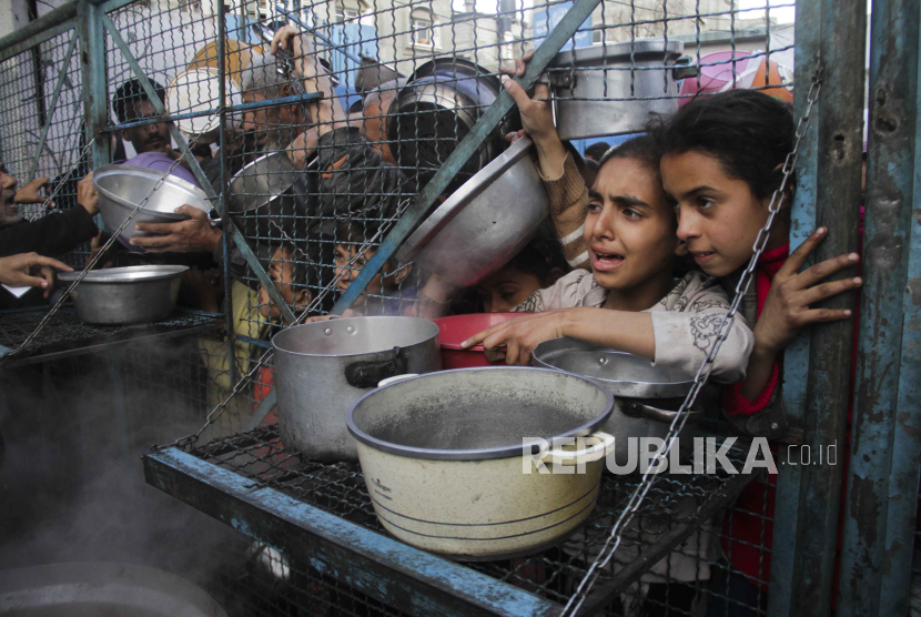  Warga Palestina mengantri untuk menerima makanan gratis di kamp pengungsi Jabaliya di Jalur Gaza pada Senin, (18/3/2024).