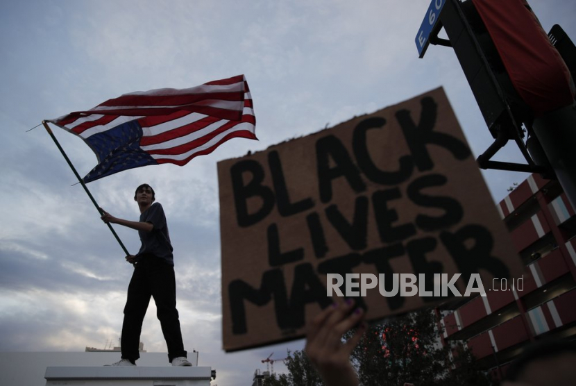 Pengunjuk rasa mengibarkan bendera pada aksi solidaritas di Las Vegas, atas tewasnya George Floyd di Minneapolis. Sejumlah rumah mode turut bersuara dan bergabung dalam aksi solidaritas Black Lives Matter.