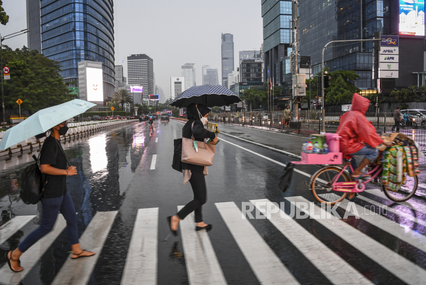 Sejumlah warga menggunakan payung saat hujan di kawasan Jalan Jenderal Sudirman, Jakarta, Selasa (4/10/2022). Badan Meteorologi Klimatologi dan Geofisika (BMKG) menyatakan potensi curah hujan dengan intensitas sedang hingga lebat yang dapat disertai kilat atau petir dan angin kencang berpotensi melanda Jakarta.