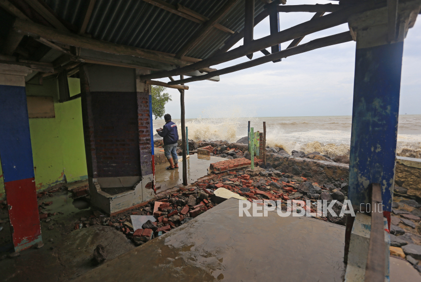 Warga melihat bangunan rumah makan yang rusak akibat diterjang ombak dan banjir rob di Desa Eretan Kulon, Kandanghaur, Kabupaten Indramayu, Jawa Barat, Senin (26/12/2022). 