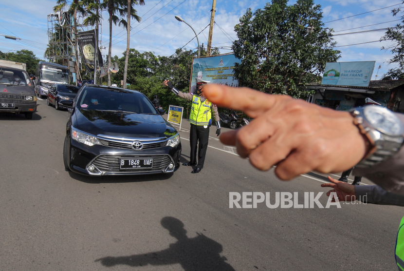 Petugas Sat Lantas Polres Bogor dan petugas Dishub Kabupaten Bogor mengarahkan kendaraan wisatawan saat penyekatan kendaraan nomor polisi ganjil genap di jalur wisata Puncak, Gadog, Kabupaten Bogor, Jawa Barat. (ilustrasi)