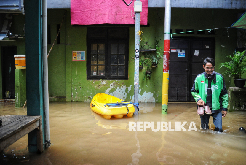 Seorang warga berjalan melintasi banjir yang melanda kawasan Kebon Pala, Kampung Melayu, Jakarta, Kamis (30/1/2025). Banjir akibat luapan Kali Ciliwung  tersebut menggenangi rumah warga dengan ketinggian 50-150 cm. Banjir ini merupakan yang kedua kalinya karena pada Rabu (29/1/2025) kawasan ini juga terendam banjir. Meski sudah dua hari berturut-turut terendam banjir luapan Kali Ciliwung,hingga Kamis siang belum ada warga yang mengungsi. Mereka memilih bertahan di lantai dua rumahnya masing-masing, dan hanya memindahkan perabot serta kendaraan sepeda motor ke tempat lebih tinggi agar tidak terendam.