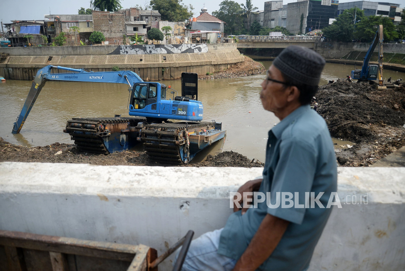 Pekerja dengan alat berat mengeruk endapan sampah bercampur lumpur di Sungai Ciliwung kawasan Jatinegara Barat, Jakarta, Kamis (23/7). Pengerukan tersebut untuk menormalkan kedalaman sungai sehingga aliran air semakin lancar. 