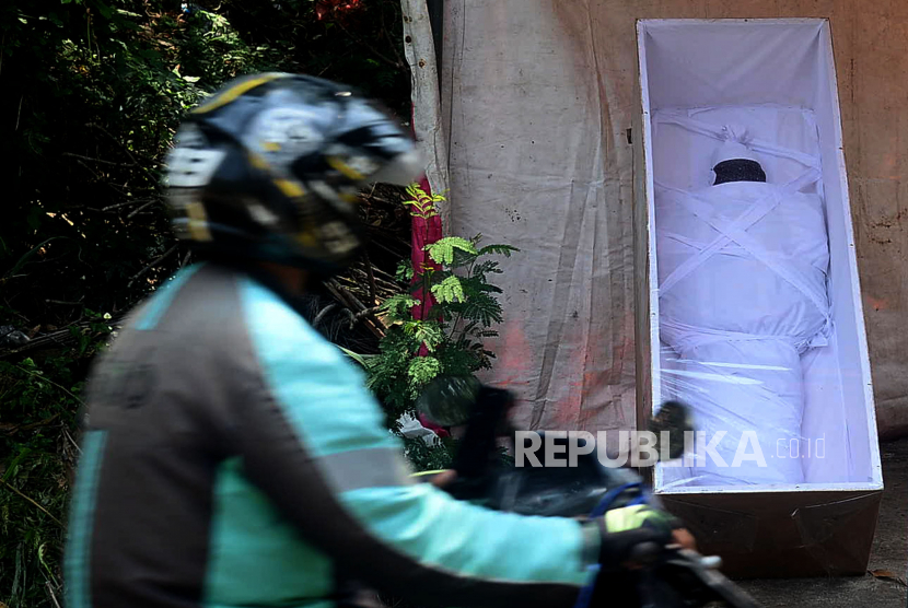 Pengguna jalan melewati imbauan untuk mematuhi protokol kesehatan yang dipasangi peti mati berisi boneka pocong bermaseker di Depok, Jawa Barat, Pemasangan peti dan pocong bermasker ini sengaja dipasang warga untuk menyampaikan pesan akan bahaya Covid-19 (ilustrasi)