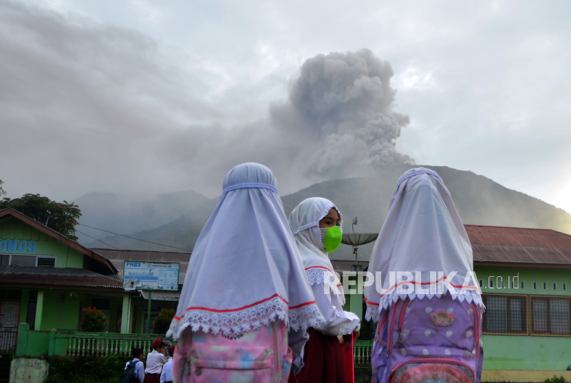 Sejumlah murid SD berada di depan sekolahnya sebelum ujian saat Gunung Marapi mengeluarkan abu vulkanik.