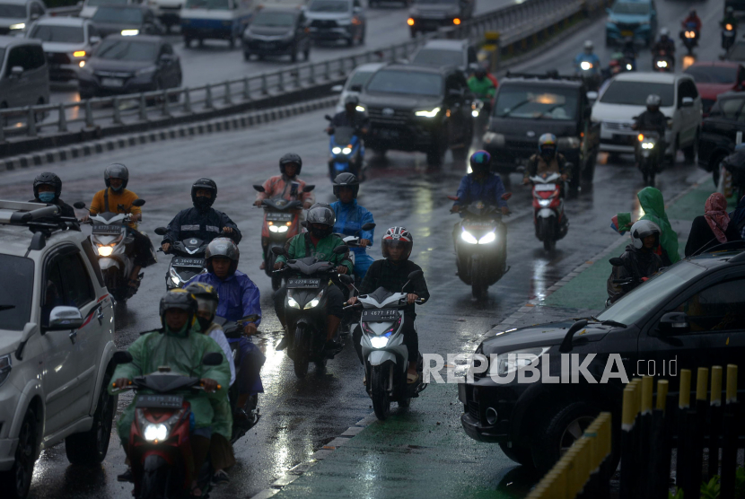 Pengendara motor dengan mengunakan mantel menerjang hujan di Jalan  Gatot Subroto, Jakarta. Pj Gubernur DKI Heru Budi melarang ASN yang beri pelayanan langsung untuk tidak WFH.