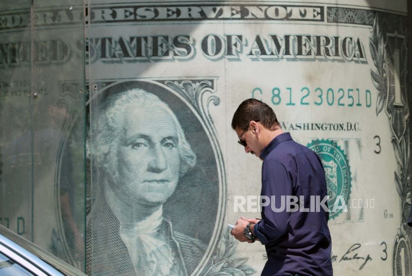 Seorang pria Mesir menunggu di luar kantor penukaran mata uang dengan gambar skala besar dolar AS, di Kairo, Mesir, 07 September 2022.