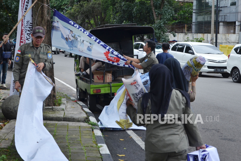 Petugas Satpol PP bersama Badan Pengawas Pemilihan Umum (Bawaslu) Bandung Wetan menertibkan Alat Peraga Kampanye (APK) yang melanggar aturan di Jalan Dipenogoro, Kota Bandung.
