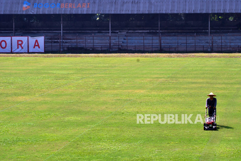 Pekerja memotong rumput lapangan sepak bola di Stadion Pajajaran, Kota Bogor, Jawa Barat.