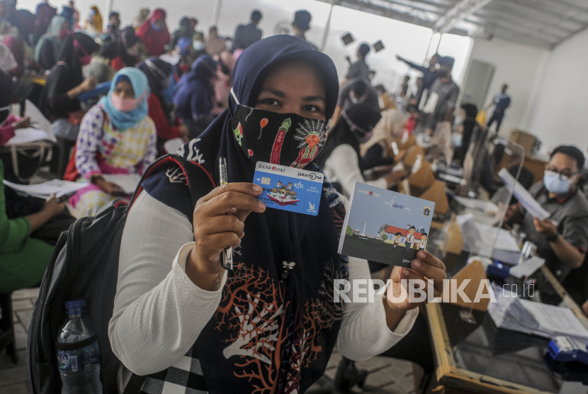 Orang tua dari anak penerima Kartu Jakarta Pintar (KJP) memperlihatkan buku rekening dan ATM Bank DKI saat penyaluran KJP plus tahap dua di kawasan Matraman, Jakarta, Rabu (24/11). 