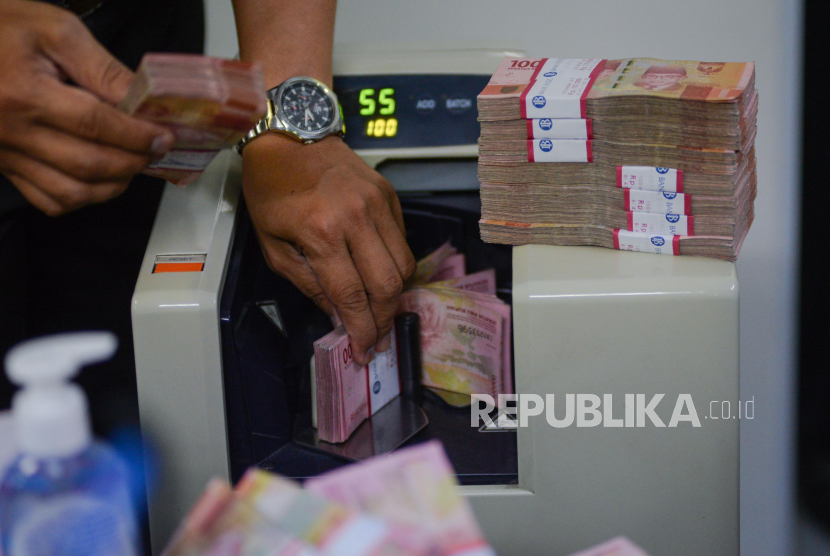 Petugas menghitung uang rupiah di salah satu gerai penukaran uang asing di Jakarta, Kamis (19/3). 