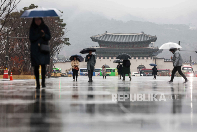 Orang-orang berjalan di Lapangan Gwanghwamun di tengah hujan pagi, di pusat kota Seoul, Korea Selatan, (15/2/2024).