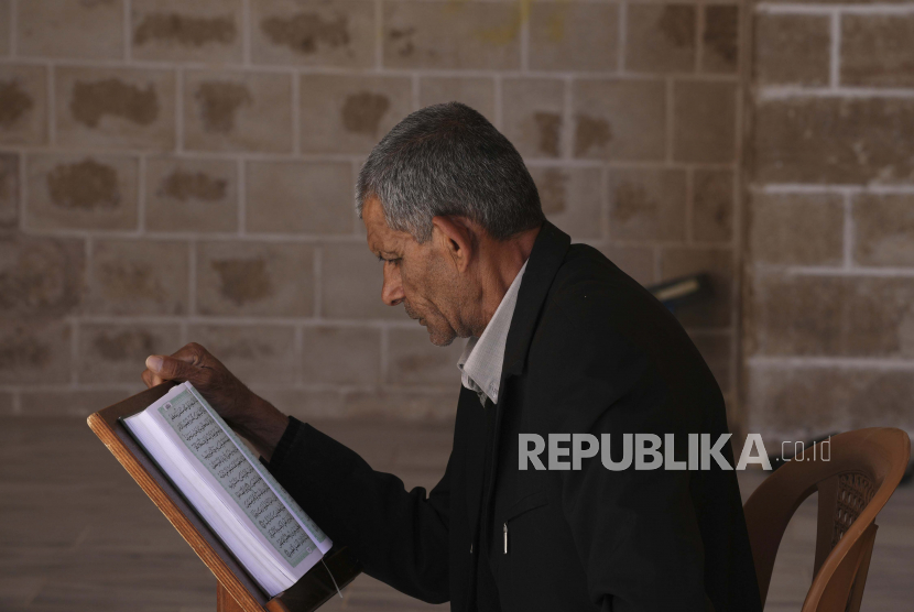 Seorang pria membacakan ayat-ayat Alquran, kitab suci umat Islam, sambil menunggu berbuka puasa di Masjid Al-Omari selama bulan suci Ramadhan di Kota Gaza, Rabu, 13 April 2022.