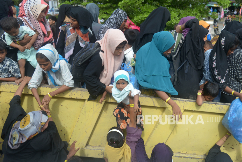 Mahasiswa bersama polisi membantu menaikan sejumlah imigran etnis Rohingya ke truk saat berlangsung pemindahan paksa di penampungan sementara gedung  Balai Meuseuraya Aceh (BMA), Banda Aceh, Aceh, Rabu (27/12/2023). Sebanyak 137 pengungsi imigran etnis Rohingya yang ditempatkan di penampungan sementara gedung BMA itu dipindahkan paksa mahasiswa setelah menggelar aksi damai ke kantor Kemenkumham Provinsi Aceh. 
