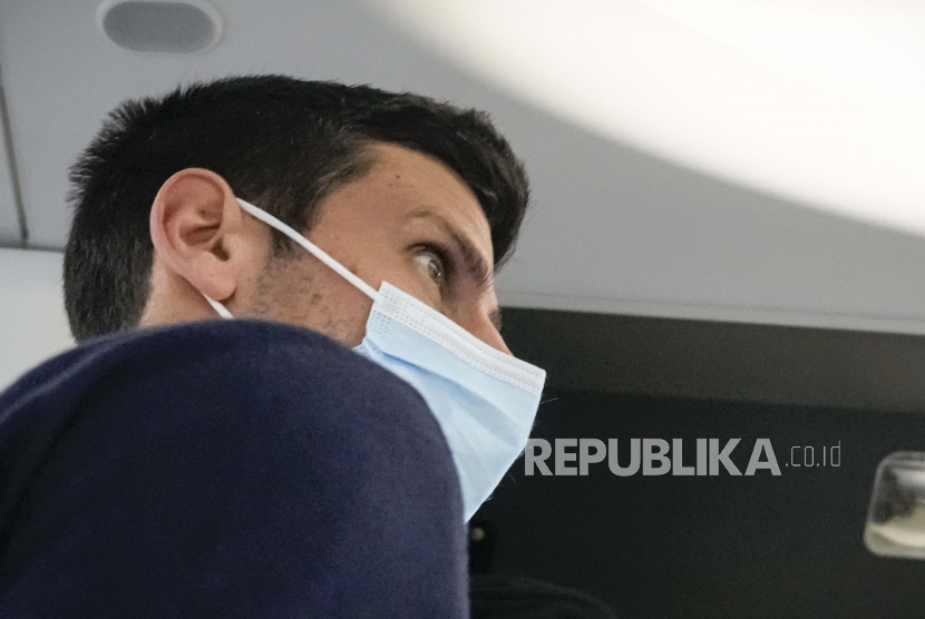 Novak Djokovic berjalan ke tempat duduknya di pesawat ke Beograd, di Dubai, Uni Emirat Arab, Senin, 17 Januari 2022. Djokovic dideportasi dari Australia pada hari  Ahad (16/1/2022) setelah kehilangan tawaran untuk tinggal di negara itu untuk mempertahankan gelar Australia Terbuka meskipun tidak divaksinasi Covid-19.