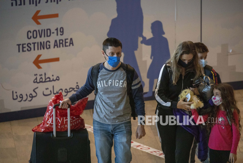  Pelancong yang mengenakan masker pelindung tiba di Bandara Ben Gurion dekat Tel Aviv, Israel, Ahad, 28 November 2021. Para menteri Israel setuju untuk melarang perjalanan ke Amerika Serikat (AS), Kanada, dan delapan negara lain pada Senin (20/12). 
