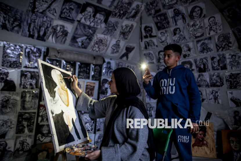 Marah Al Za anin, 18, works on a drawing inside her tent in Gaza City Al-Rimal neighborhood on January 28, 2026, using her brotherís phone flashlight to paint after dark. The young Palestinian has turned her displacement shelter into an art space, channeling the trauma of war into canvases that reflect resilience amid ongoing hardship.
