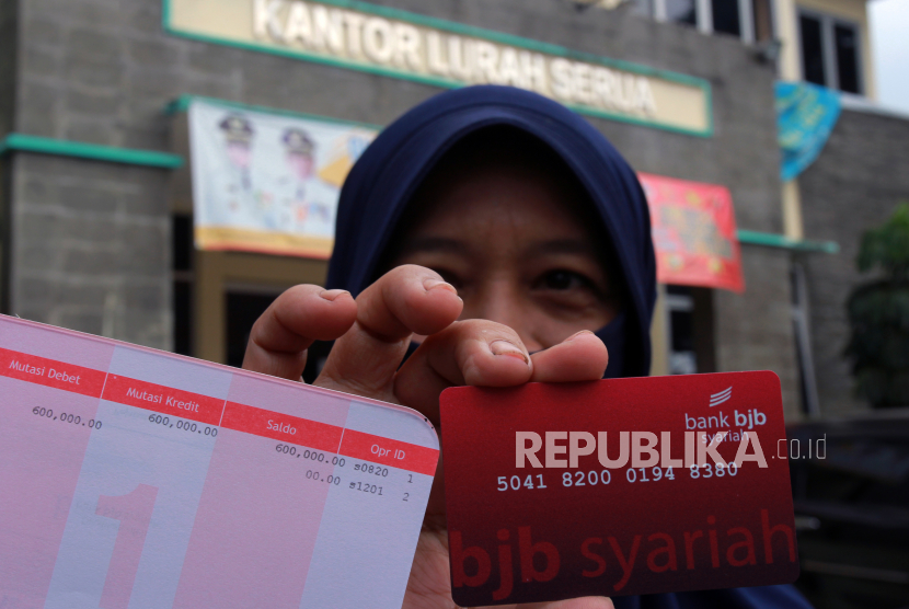 Warga menunjukan buku tabungan dan kartu ATM berisi uang Rp 600 ribu usai melakukan pencairan Bantuan Sosial (Bansos) yang diperuntukkan bagi masyarakat terdampak pandemi COVID-19 dari Pemerintah Provinsi Banten di Serua, Tangerang Selatan, Banten, Rabu (6/5/2020). 