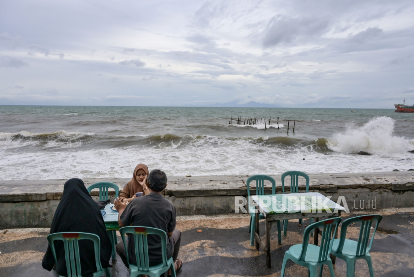 Warga duduk di pinggir pantai saat terjadi gelombang tinggi di Pantai Ampenan, Mataram, NTB, Ahad (10/3/2024). BMKG menyebut sistem peringatan dini sangat penting guna meningkatkan kesiapsiagaan.