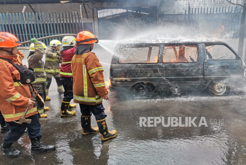 Petugas pemadam kebakaran menangani mobil Carry pembawa jeriken BBM yang terbakar di Jalan Ibrahim Adjie, Kiaracondong, Kota Bandung, Jawa Barat, Senin (13/2/2023). 