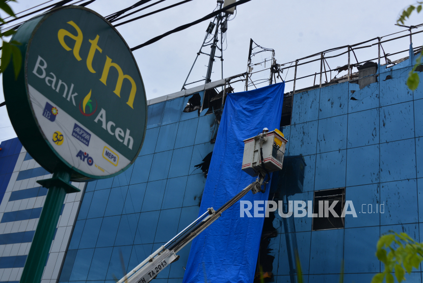 Pekerja membersihkan pecahan kaca pada Kantor Pusat Operasional Bank Aceh.