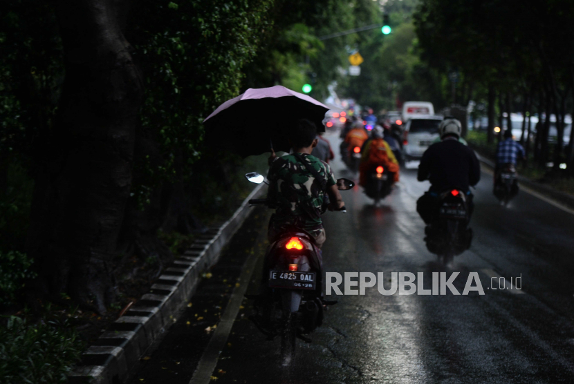 Pengendara motor melintas menggunakan payung di Jalan Kolonel Sugiono, Duren Sawit, Jakarta, Senin (27/3/2023). Badan Meteorologi, Klimatologi, dan Geofisika (BMKG) mengatakan hujan disertai kilat atau petir dan angin kencang akan melanda sebagian wilayah Jakarta.