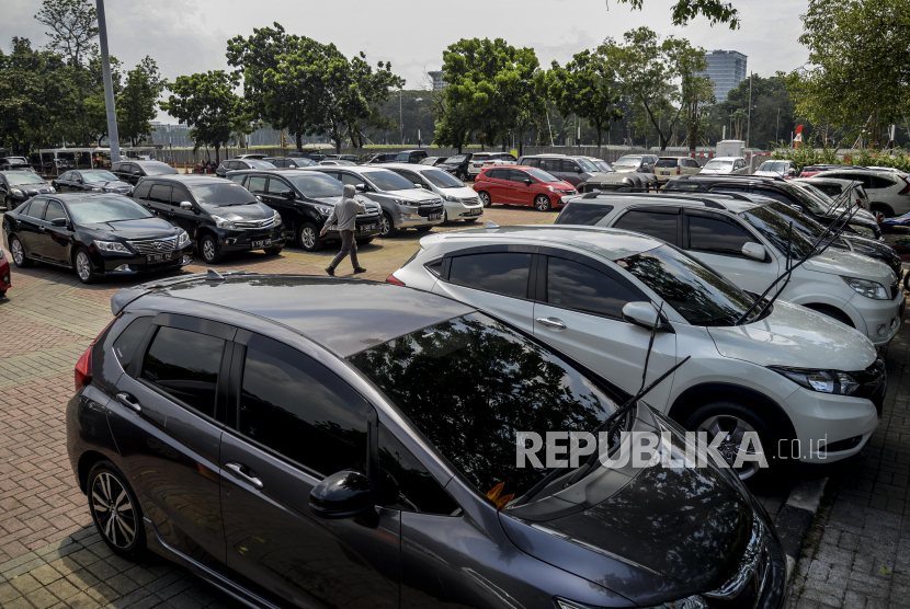 Warga berjalan di dekat kendaraan yang diparkirkan di area parkiran IRTI, Monas, Jakarta, Rabu (9/9). Pemerintah Provinsi DKI Jakarta menaikan pajak parkir yang semula sebesar 20 persen menjadi 30 persen yang tercantum dalam perubahan Peraturan Daerah (Perda) Nomor 16 Tahun 2010 tentang Pajak Parkir. Republika/Putra M. Akbar