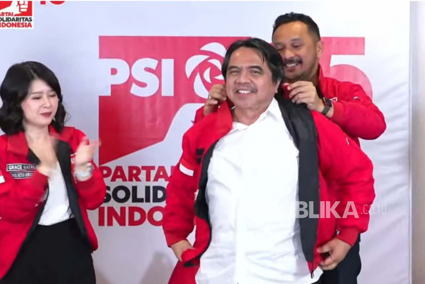 Ketua Umum Partai Solidaritas Indonesia (PSI), Giring Ganesha memasangkan jaket partainya kepada pegiat media sosial Ade Armando di Kantor DPP PSI, Jakarta, Selasa (11/4/2023).