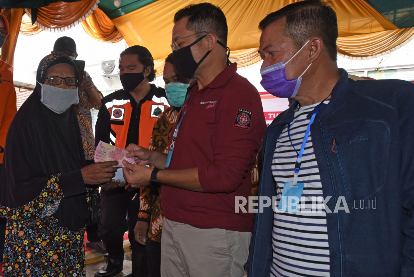 Menteri Sosial Juliari Batubara (kedua kanan) disaksikan Wali Kota Serang Syafrudin (kanan) menyerahkan Bantuan Sosial Tunai (BST) kepada warga penerima bantuan di Kantor Pos Serang, Banten, Sabtu (9/5/2020). Sebanyak 343