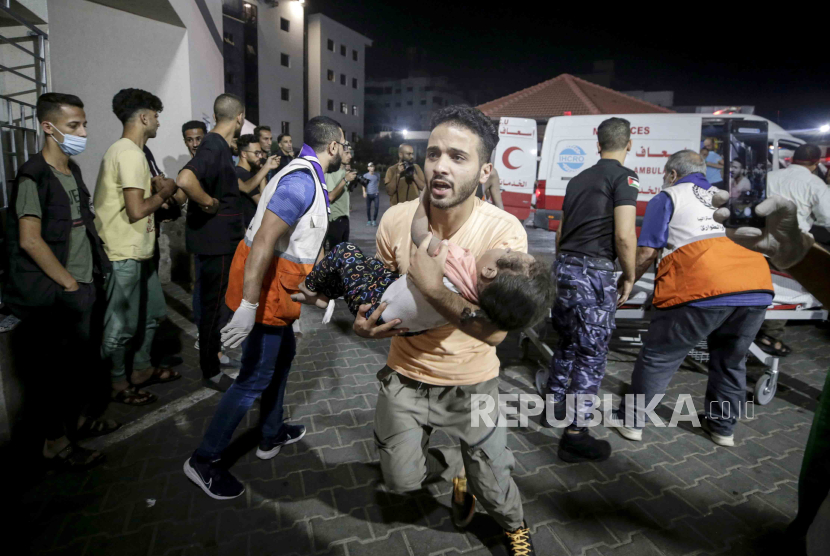 Seorang pria Palestina membawa seorang anak yang terluka di rumah sakit Al-Shifa di Kota Gaza, Palestina, 9 Oktober 2023. 