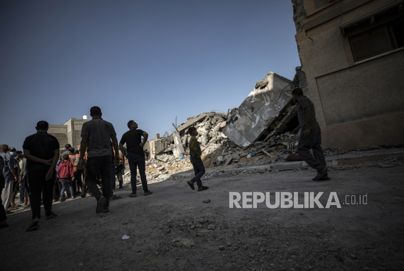 Warga Palestina mencari jenazah dan korban selamat di reruntuhan bangunan tempat tinggal yang rata akibat serangan udara Israel.
