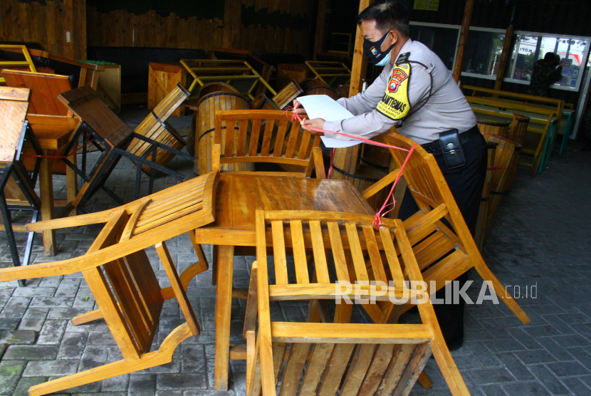 Petugas mengikat kursi sebuah kafe agar tidak digunakan saat pelaksanaan Pemberlakuan Pembatasan Kegiatan Masyarakat (PPKM) Darurat.