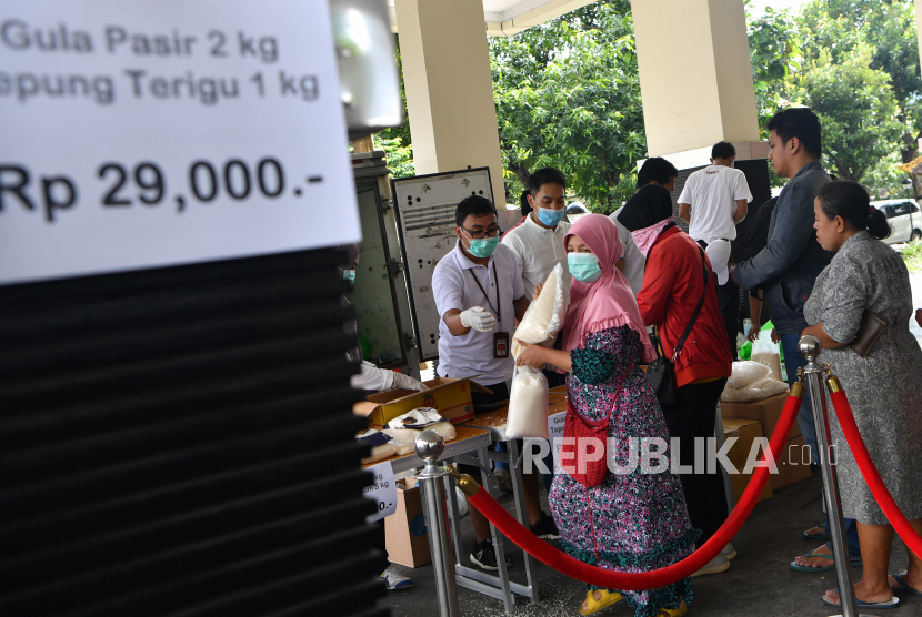 Warga mengantre untuk membeli beras dan gula pasir saat digelar operasi pasar murah di halaman Kantor Bulog Divre Jatim, Surabaya, Jawa TImur, Sabtu (21/3/2020). Pasar murah tersebut digelar guna mengantisipasi adanya 