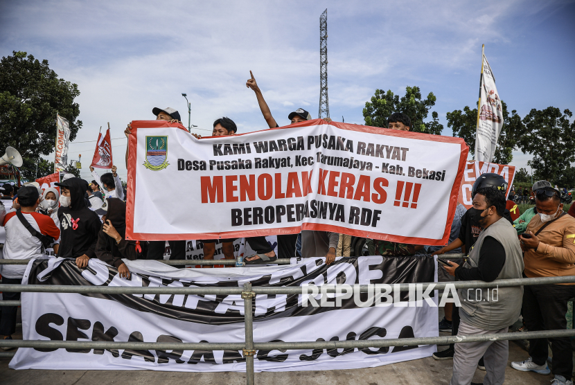 Sejumlah warga membentangkan spanduk saat mengikuti unjuk rasa di depan kawasan Refuse Derived Fuel (RDF) Plant, Rorotan, Jakarta Utara, Jumat (21/3/2025). Dalam aksinya mereka menuntut untuk RDF Plant tersebut ditutup karena telah mencemari udara di lingkungan sekitar. 