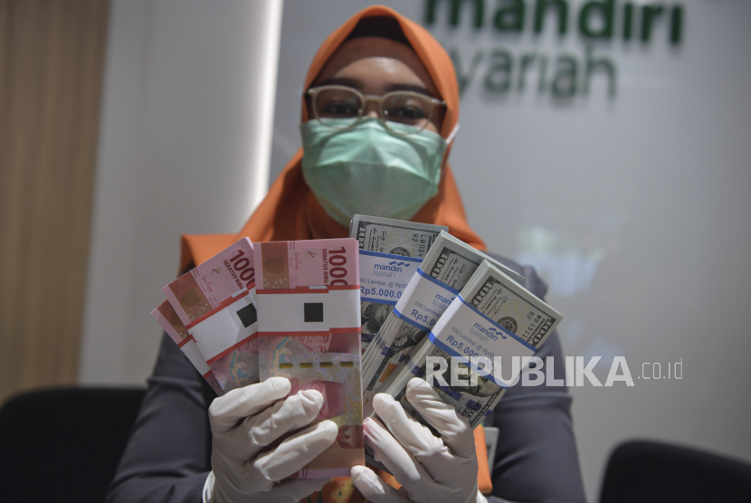 Karyawan menunjukkan uang rupiah dan dolar AS di Bank Mandiri Syariah, Jakarta, Senin (20/4). Mandiri Syariah mendukung wakaf produktif melalui Cash Waqf Linked Sukuk (CWLS) Aceh. 