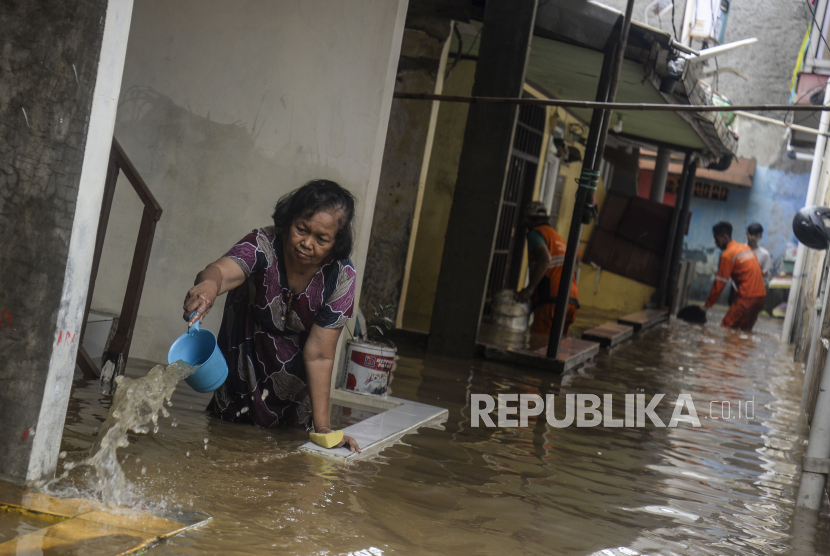 Warga membuang air dari rumahnya yang berada di samping Sungai Ciliwung saat terjadi banjir di kawasan Rawajati, Kecamatan Pancoran, Jakarta Selatan, Senin (10/10/2022).